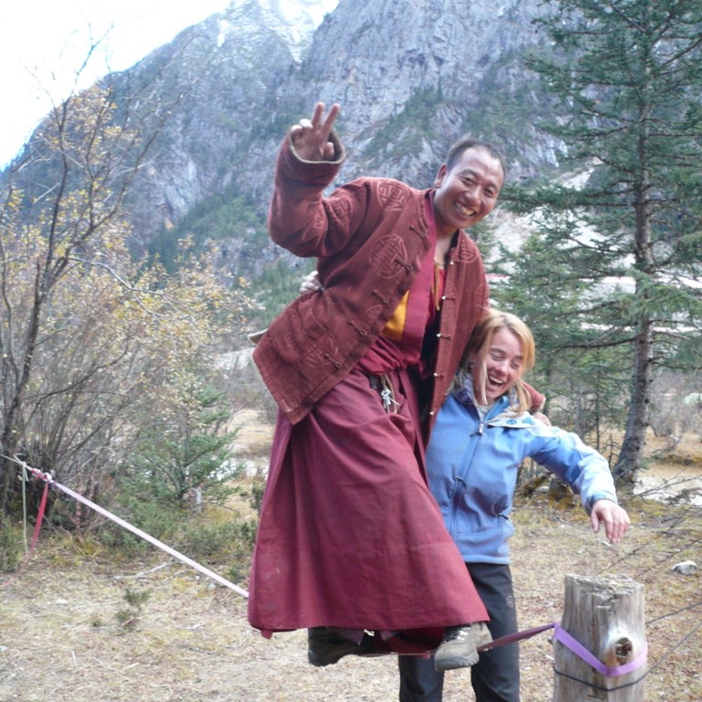 A man and woman pose for the camera while holding onto a stick.