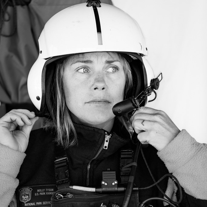 A woman wearing a helmet and holding onto some wires