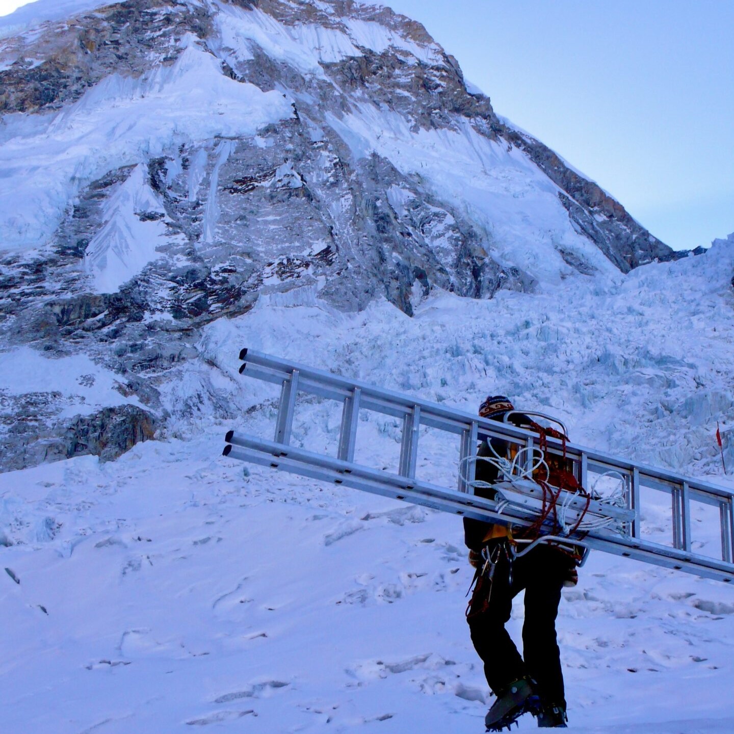 A man holding a ladder in the snow.