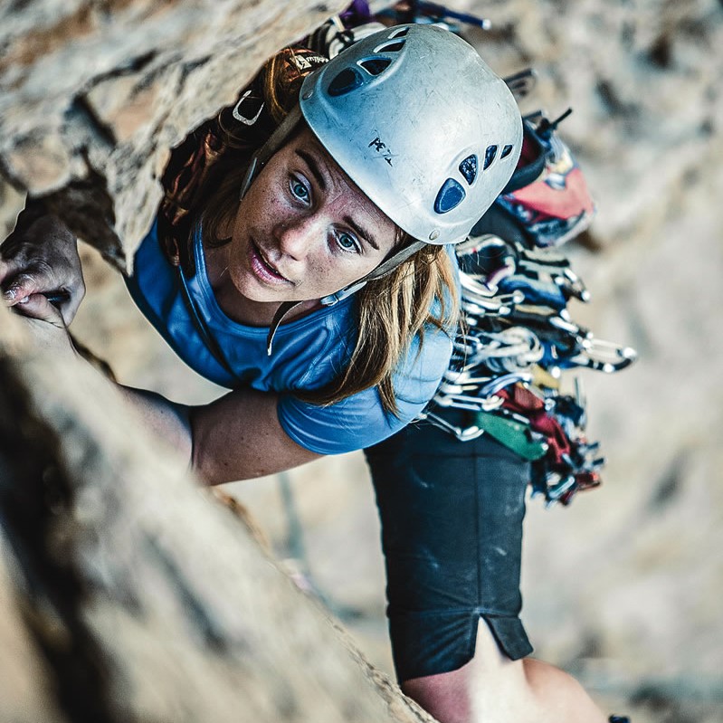 A woman climbing up the side of a rock wall.